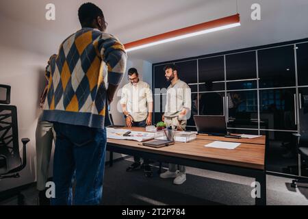 A diverse team of architects and business professionals collaborate in a boardroom, discussing a blueprint for a project. Stock Photo