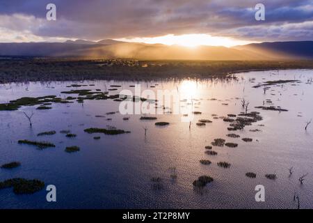 Aerial view of dramatic light breaking through clouds over a mountain range and reflecting on a lake at Lake Fyans in Victoria, Australia Stock Photo