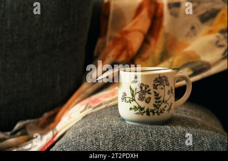 Cup of coffee on the rim of gray sofa Stock Photo