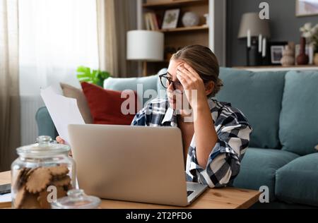 People, accounting, finances, family budget and financial issues concept. Serious young European woman calculating domestic expenses, sitting at dinin Stock Photo