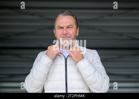 Portrait of a thoughtful attractive man in white winter jacket with his hands on the collar of the jacket Stock Photo