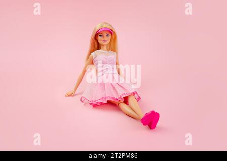 October 9, 2023. Barnaul, Russia: Barbie doll with loose blond hair in a pink dress sitting on a pink background. Stock Photo