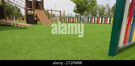 Artificial green grass floor on playground. Colourful rows of painted posts arround Stock Photo