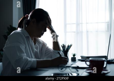 Hard think on analysis in the work. Young asian business woman is working on pressure in office. Tired business woman sleepy and bored from sitting at Stock Photo