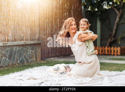 Mother and daughter enjoying a sunny weather in the garden. Piggyback. Copy space Stock Photo