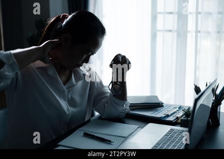 Hard think on analysis in the work. Young asian business woman is working on pressure in office. Tired business woman sleepy and bored from sitting at Stock Photo