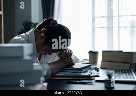 Hard think on analysis in the work. Young asian business woman is working on pressure in office. Tired business woman sleepy and bored from sitting at Stock Photo