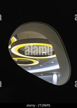 Looking through the Glass mirrored wall panels in the living room can see the hanging rounded ceiling mounted light fixtures with modern LED light bul Stock Photo