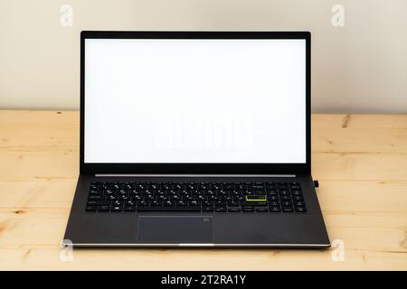 A photo of a laptop on a wooden desk showing a blank screen. Stock Photo