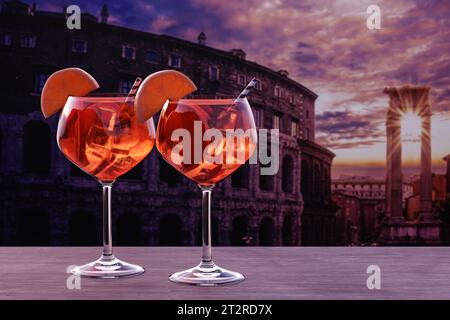 Spritz cocktail on a table with view of sunset over Rome Colosseum in Rome, Italy Stock Photo