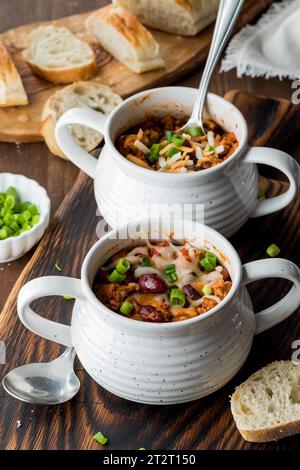 Homemade chili con carne in soup crocks, served with a crusty baguette. Stock Photo
