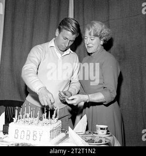 File photo dated 13-10-1958 of Manchester United and England footballer Bobby Charlton, aided by his mother, Betty Charlton, lights the candles on his 21st birthday cake at his home at Ashington. Sir Bobby Charlton has died aged 86, his family have announced. Issue date: Saturday October 21, 2023. Stock Photo