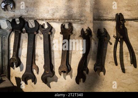 Old wrenches on wooden industrial wall. Tool on the wall of a locksmith against  old grunge background Stock Photo