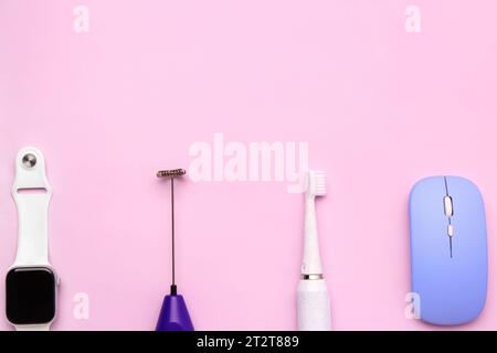 Smartwatch with mixer, electric toothbrush and computer mouse on pink background Stock Photo