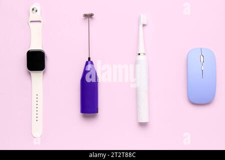 Smartwatch with mixer, electric toothbrush and computer mouse on pink background Stock Photo