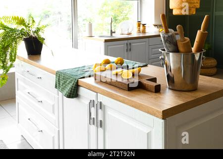 Wooden board with fresh lemons and rolling pins on wooden countertop in modern kitchen Stock Photo