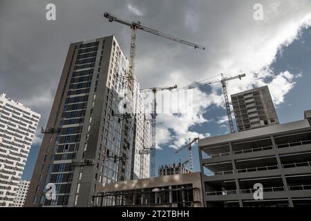 Concrete constructions and cranes on the construction site, wide angle dynamic shot, bottom view. Stock Photo
