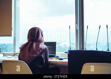 A young woman IT developer is deeply focused on her work as she diligently types away on her laptop Stock Photo