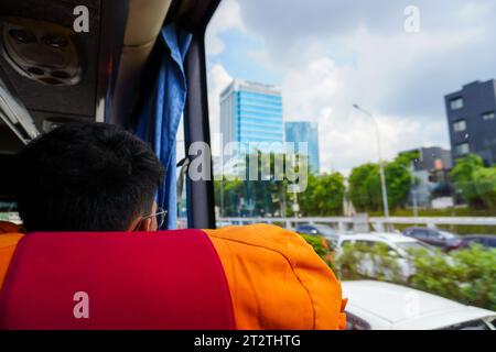 Looking out the window of a moving bus, a man is captivated by the impressive cityscape of skyscrapers and busy roads Stock Photo