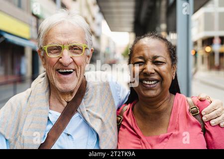 Happy multiracial senior friends having fun while waiting at the bus station Stock Photo