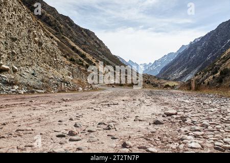 Rocky gravel road in the hillside leading into the mountains, bottom view. Early spring in nature Stock Photo