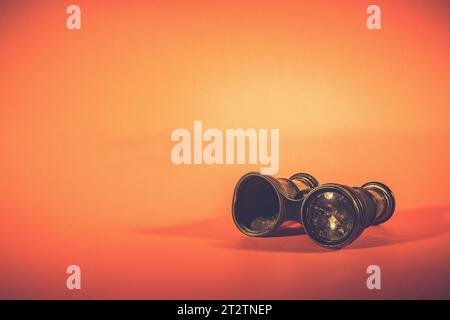 Old binocular with a broken glass, with a subtle shadow on an orange background Stock Photo
