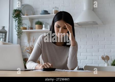 Unhappy stressed Asian woman checking bills, having money problem Stock Photo