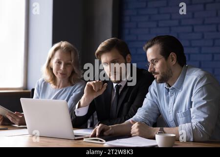 Three teammates working together use laptop in office Stock Photo