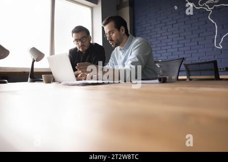 Two businessmen working together on project using laptop at workplace Stock Photo