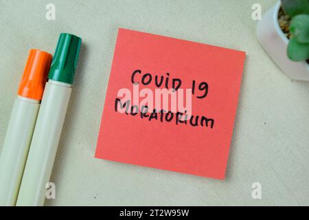 Concept of Covid 19 Moratorium write on sticky notes isolated on Wooden Table. Stock Photo