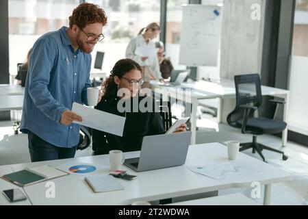 Two diverse business colleagues disscuss biz issue while use laptop in office background Stock Photo