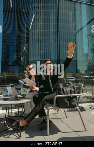 Business colleagues working with documents sitting on cafe terrace and showing something Stock Photo
