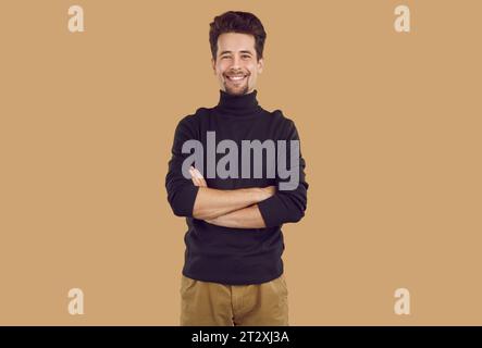 Portrait of happy handsome young man posing with folded hands Stock Photo