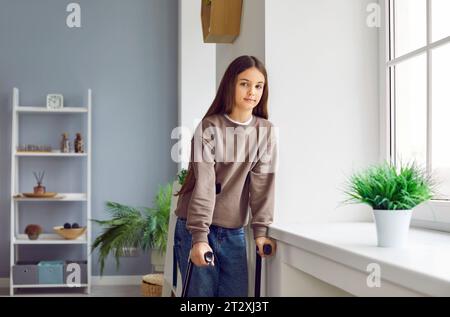 Portrait of handicapped young girl child looking at camera standing with crutches. Stock Photo
