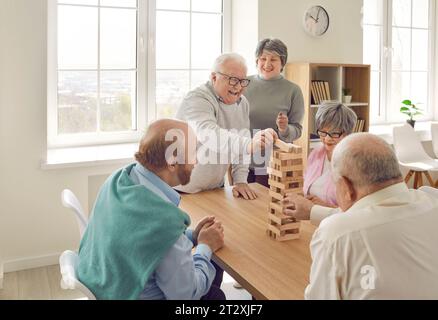 Cheerful retired friends playing jenga board game at home Stock Photo