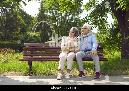 Happy mature couple sit on bench in park relaxing Stock Photo