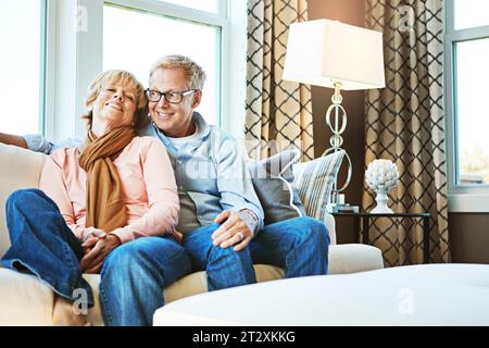 Relax, happy and old couple on sofa in home for bonding, healthy relationship and marriage. Retirement, hug and senior man and woman on couch for love Stock Photo