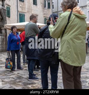 Kotor, Montenegro, Apr 17, 2023: A group of tourists gathered around guide at the Flour Square in Old Town Stock Photo