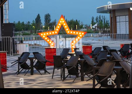 Evening view of a street cafe with a beautiful pleasant illumination without people with assembled chairs. Stock Photo