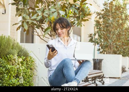 Young woman with smartphone and laptop doing consultation or e-commerce online. Stock Photo