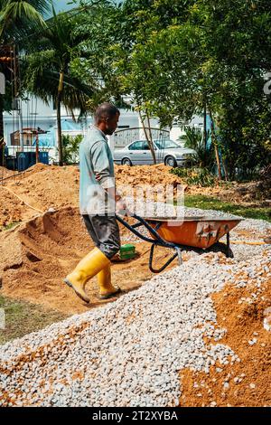 Selangor, Malaysia - October 21, 2023 Workers using wheelbarrow at a house renovation constructions. Stock Photo