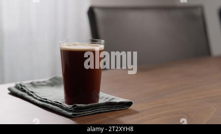 nitro coffee in thin glass on walnut table, wide photo Stock Photo