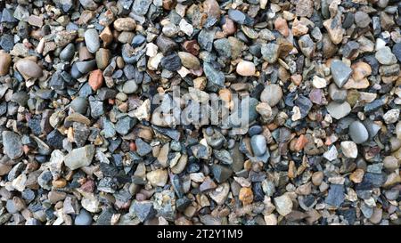 gray gravel with splashes of red and white as a natural texture, sharp wet pebbles top view as a finely textured background, screenings Stock Photo