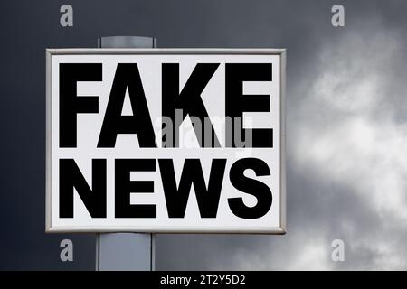 Close-up on a white billboard against a stormy sky with the message "Fake news" written in the middle. Stock Photo
