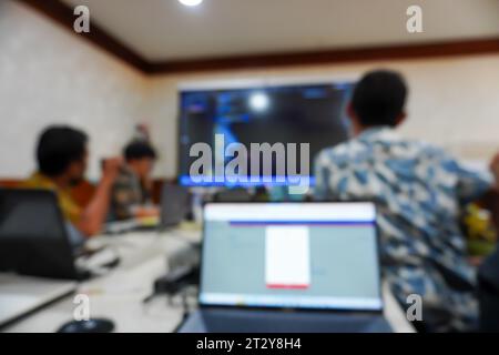 a group of office workers gathered around a conference table, their figures elegantly blurred as they engage in attentive observation of a team Stock Photo