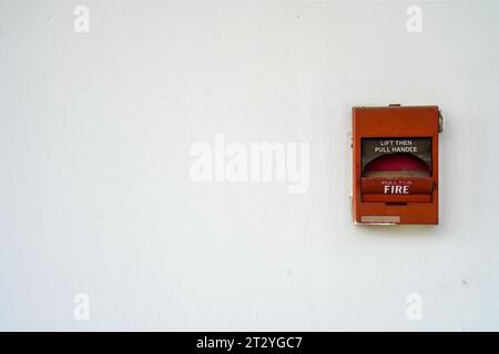 Broken red fire alarm box against Clean White Wall with copy space for text Stock Photo