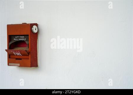 Broken red fire alarm box against Clean White Wall with copy space for text Stock Photo