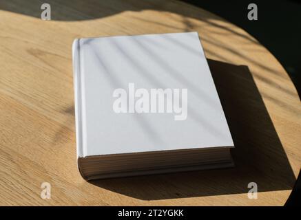 Book cover, blank hardcover lying on wooden table with sun light, day sunlight Stock Photo