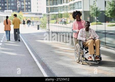 Smiling African American woman walking with her friend with disability in the city Stock Photo