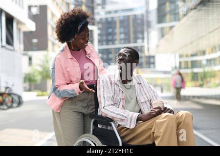Young African American couple walking in the city, woman talking to her friend with disability Stock Photo